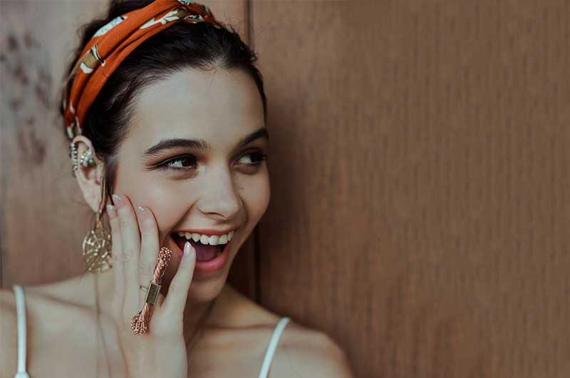 Girl in a tank top wearing dangle earrings laughing